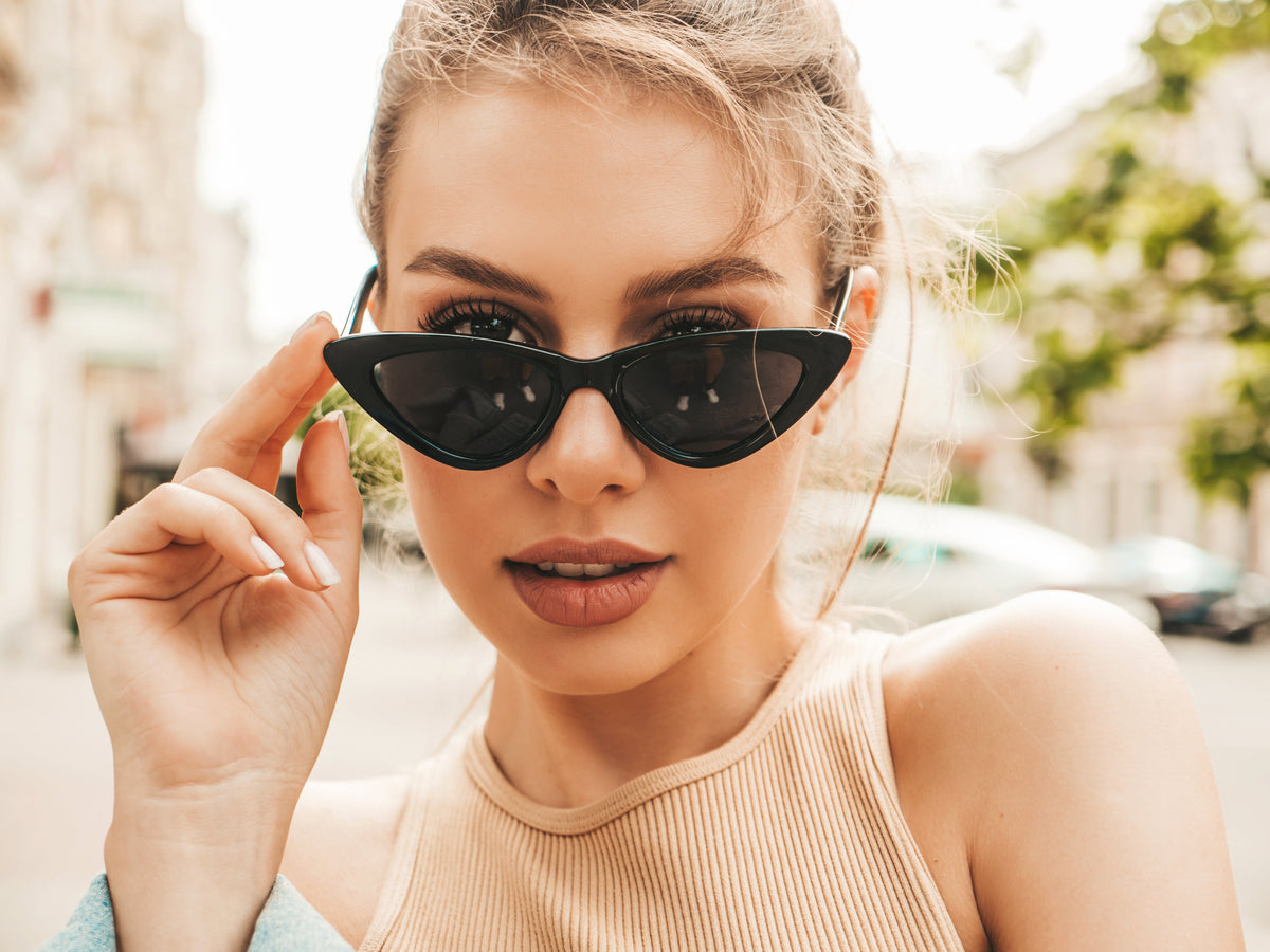 Primer plano de una mujer con gafas de sol negras de montura cat-eye al aire libre