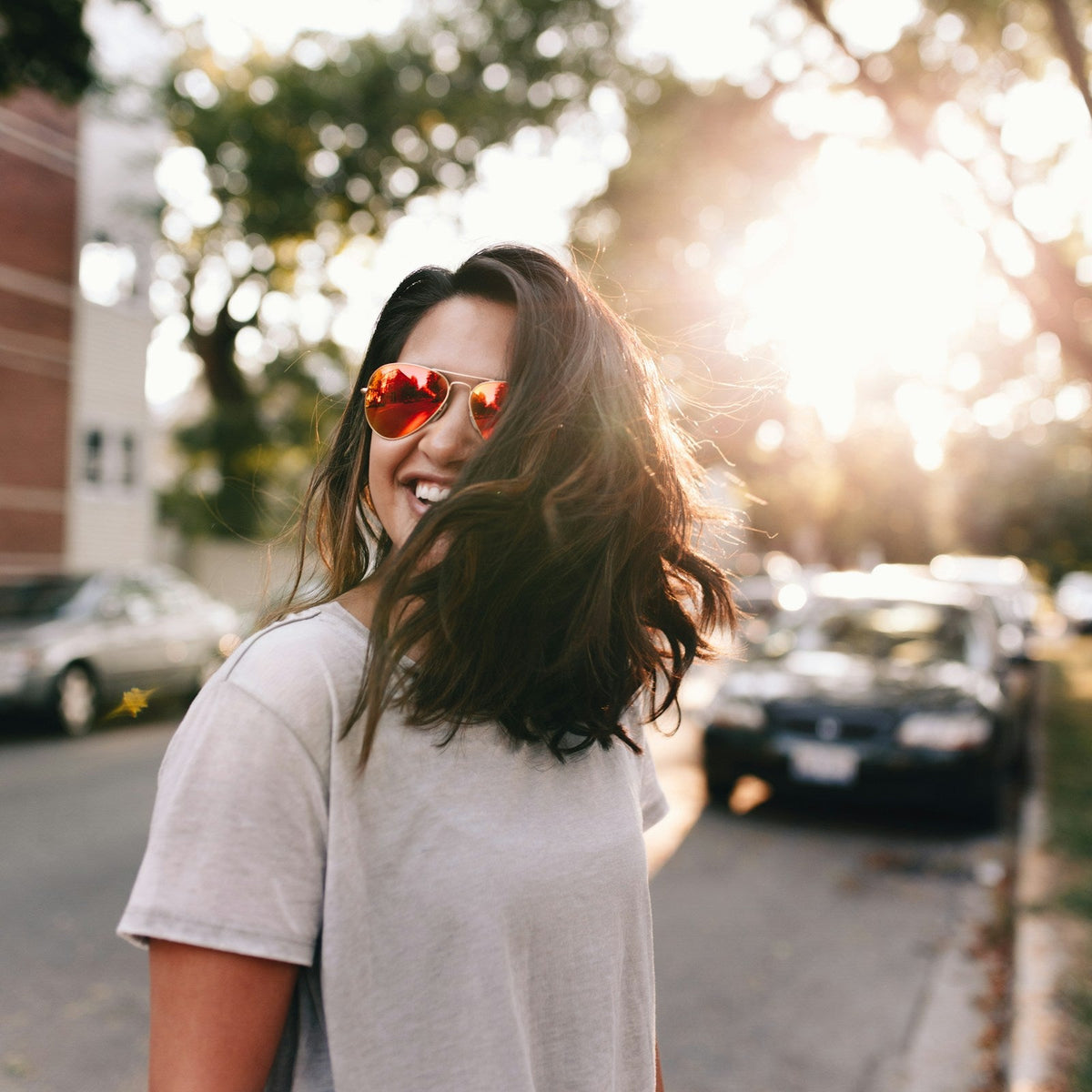 Mujer sonríe al aire libre con gafas de sol de lentes rojas reflectantes