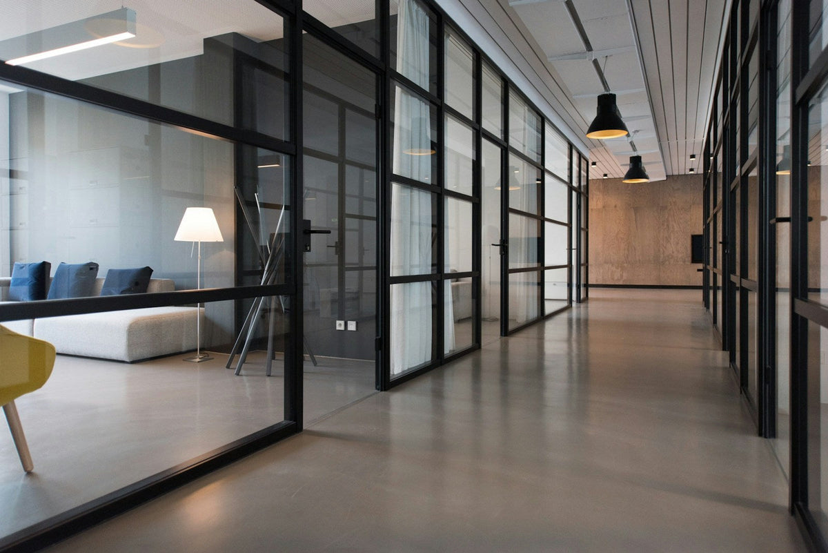Pasillo de oficina moderno con divisiones de cristal y líneas arquitectónicas minimalistas