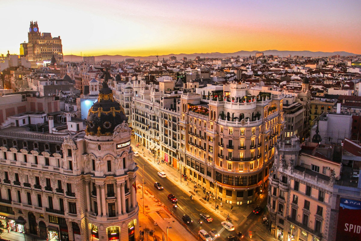 Vista de una gran avenida urbana con edificios históricos iluminados al atardecer