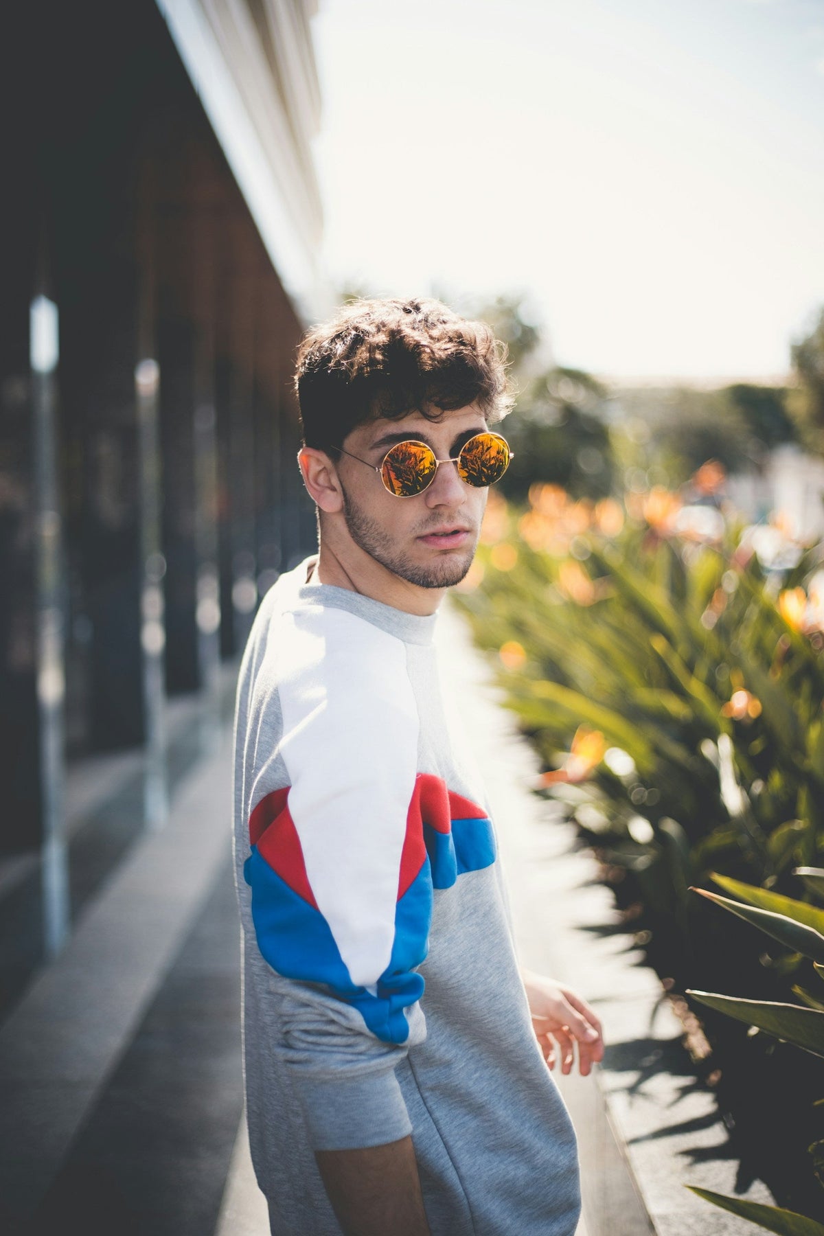 Hombre joven con gafas de sol de lentes anaranjadas y sudadera deportiva al aire libre