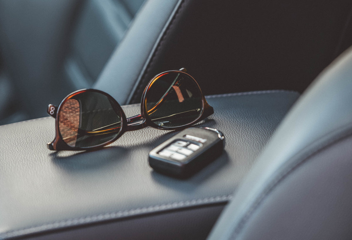 Gafas de sol oscuras y llave de coche sobre un asiento de automóvil